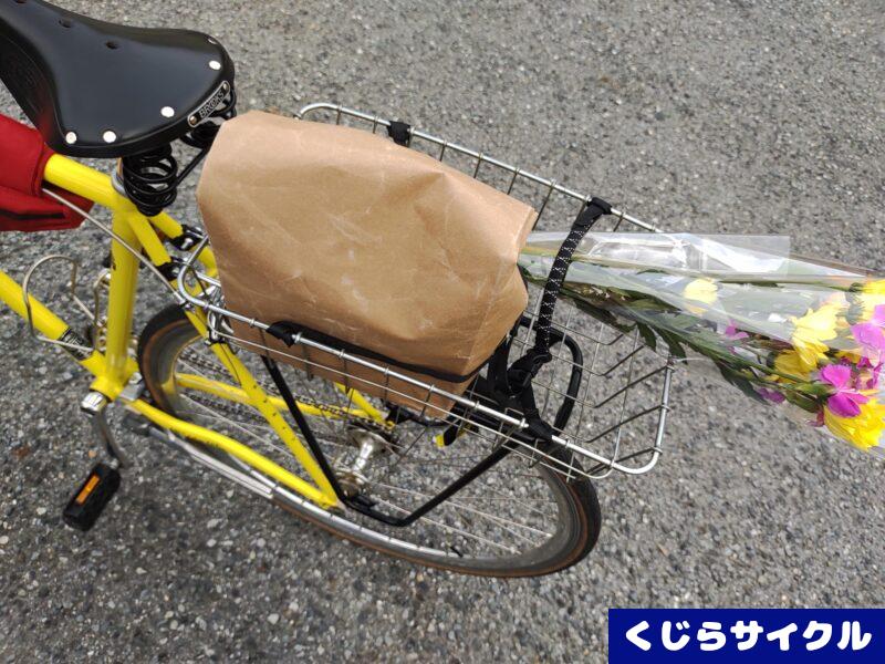 自転車のかごに積まれた紙袋と花束